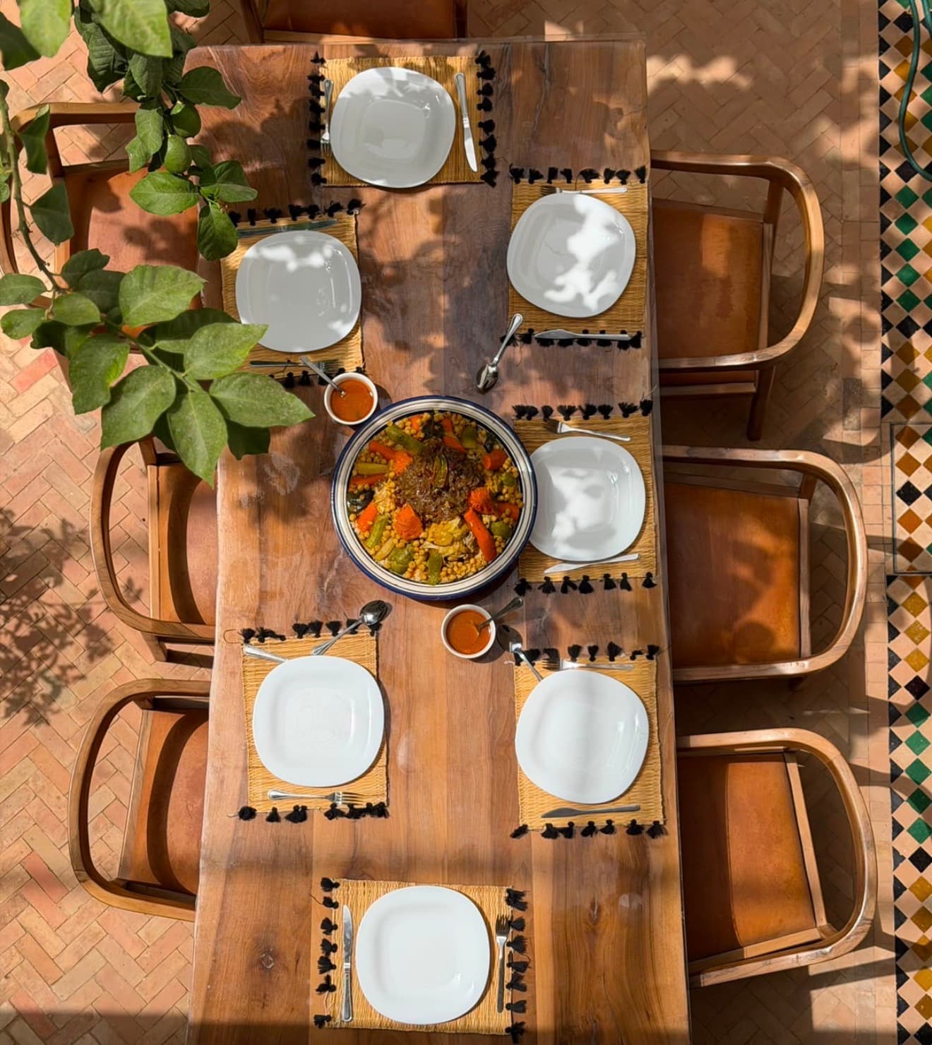 Couscous table spread: communal table with a large couscous bowl, the kind of Moroccan course a private chef can prepare at Riad Bab Atlas.