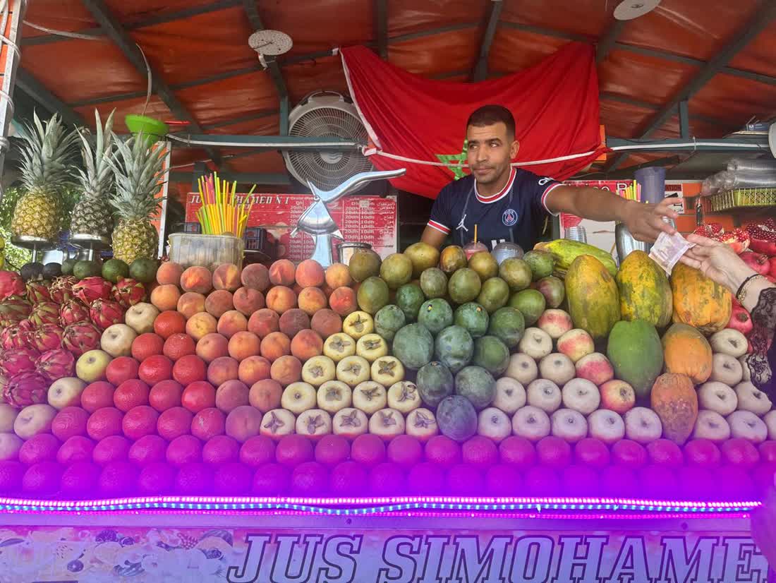 A fresh juice cart in Jemaa el-Fna with a pyramid of fruit