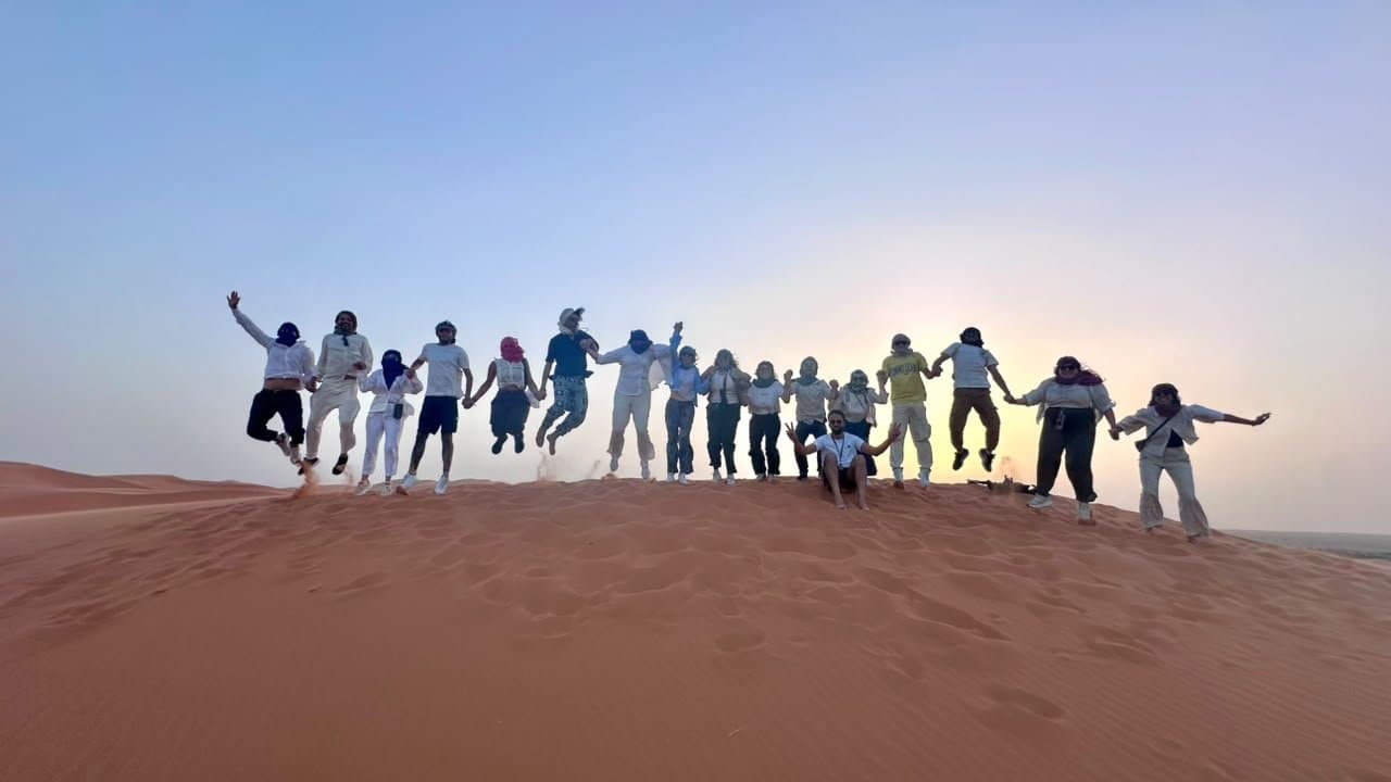 A group standing on the Erg Chebbi dunes near Merzouga at sunset.