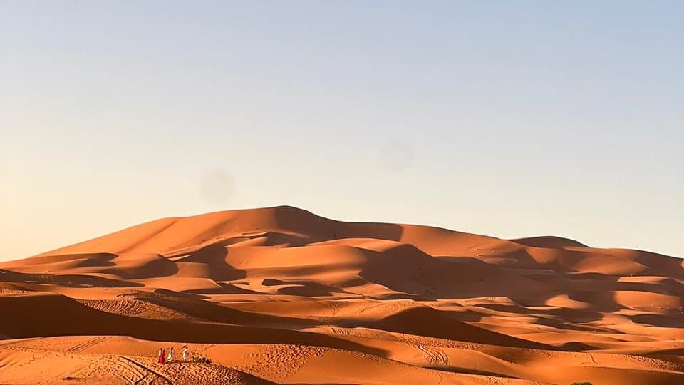 Erg Chebbi dunes near Merzouga at golden hour, with footprints across the sand.
