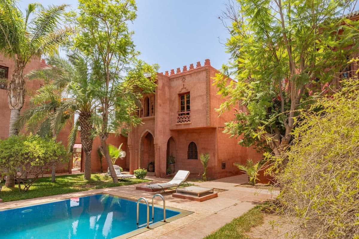 Pool courtyard, palms, and pointed arch at Riad Bab Atlas.
