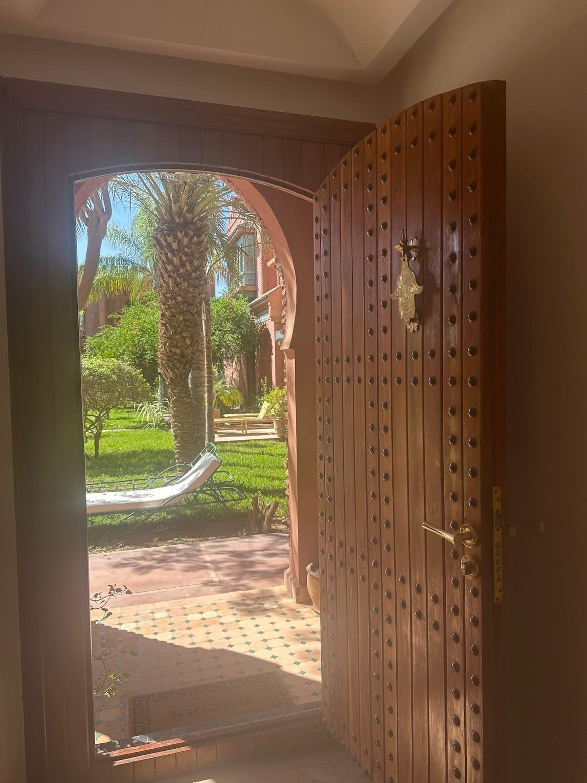 Hamsa knocker and zellige threshold looking out to the garden at Riad Bab Atlas.